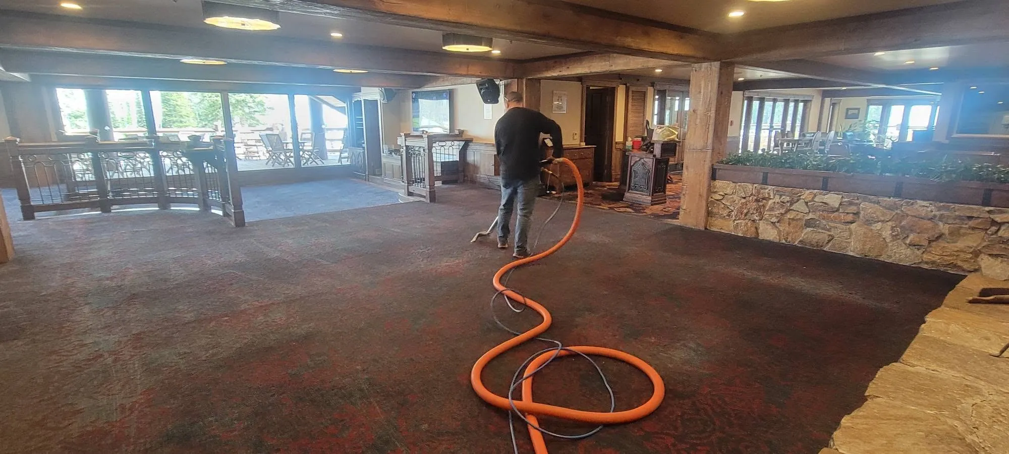 A large Park City lodge interior being cleaned, extraction hose running the length of the room